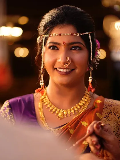 A beautiful close-up with a soft, out-of-focus background. The bride's smile and the traditional mundavalya are the stars of this shot.