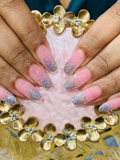 A playful pink and blue glitter gradient on long, rounded nail extensions for a touch of sparkle.