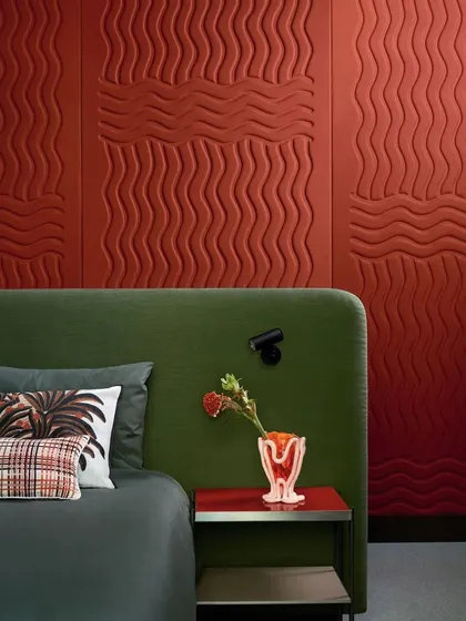 A closer view of the "Wave Flanelle" design, highlighting the striking graphic relief of its sinuous quilted curves. The rich terracotta color adds warmth and drama to this contemporary bedroom.