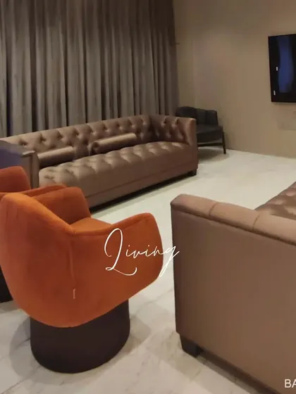 This living room uses a mix of seating options, including tufted sofas and modern swivel chairs in contrasting colors, to create a dynamic and comfortable social space.