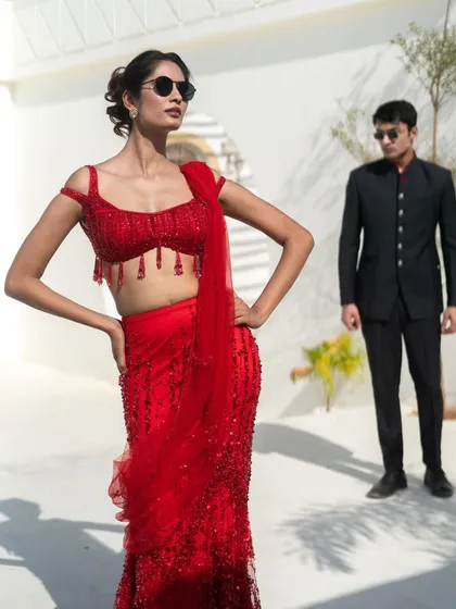 Get on-trend looks without breaking the bank. This couple is styled in a fiery red sequin saree and a sleek black bandhgala suit, a perfect look for a modern reception.
