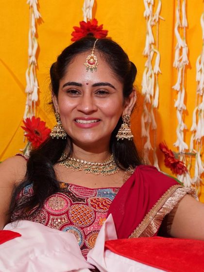 A smiling portrait of the bride during her 'ghar wali mehendi'. Her light kundan jewellery, including a necklace, jhumkas, and maangtikka, adds just the right amount of sparkle to her look.
