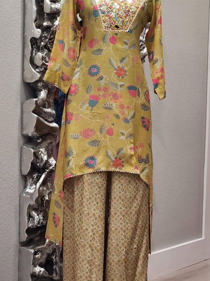 A high-low floral kurta paired with brocade pants. The neckline is embellished with colorful mirror work, making it a festive and fun outfit.