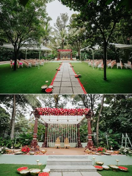 A wide shot of the beautiful outdoor wedding mandap, decorated with red and white flowers, set in a lush green lawn.