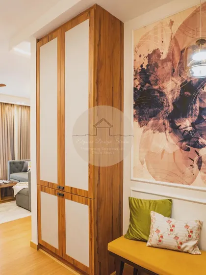 An entryway featuring a tall storage unit in wood and white laminate, paired with a mustard yellow bench. The large abstract artwork adds a pop of color and personality.