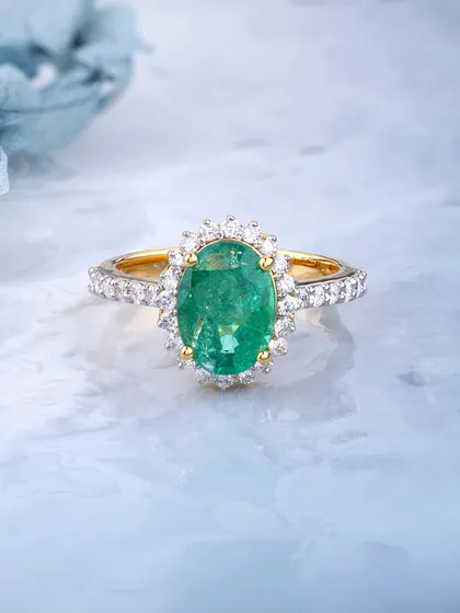 A classic halo design with a vibrant heart. This ring features a large oval Zambian emerald surrounded by a halo of brilliant diamonds, set on a diamond pavé band. The contrast between the deep green and the sparkling diamonds is timeless.