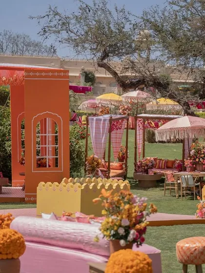 An overview of the vibrant Haldi setup, showing the various seating areas, canopies, and decor elements that create a festive village or 'pind' atmosphere.