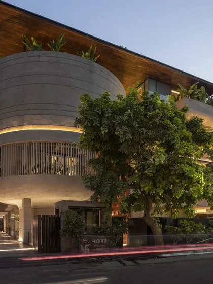 The 'Nadhyavart' residence at dusk, where strategic lighting highlights its unique form. The blend of a cylindrical concrete volume, vertical louvers, and a cantilevered roof creates a captivating architectural masterpiece.