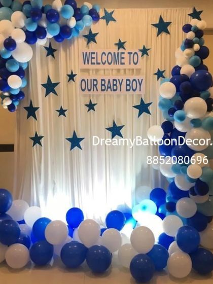 A 'Welcome to our Baby Boy' backdrop. This setup features a white curtain with blue star cutouts and a beautiful balloon garland in shades of blue and white.