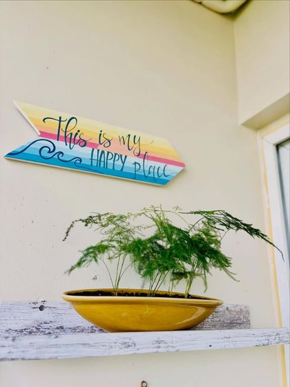 This asparagus fern in a bright yellow bowl-planter perfectly complements the "This is my happy place" sign. It’s a small touch that adds a lot of personality and joy to the space.