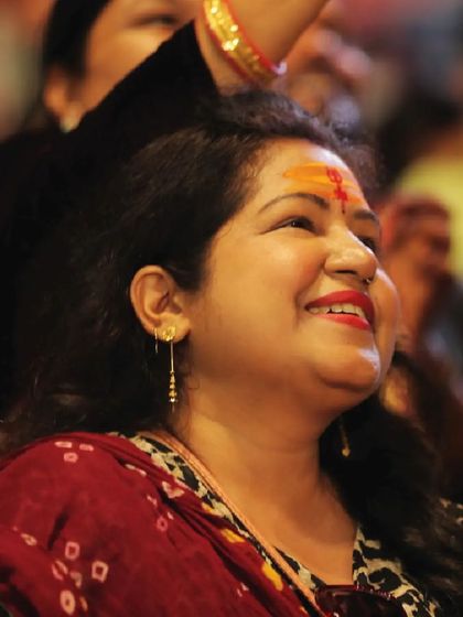 A woman smiles, her face illuminated by the glow of the drone show in Varanasi. These are the moments of personal connection and happiness that we strive to create.