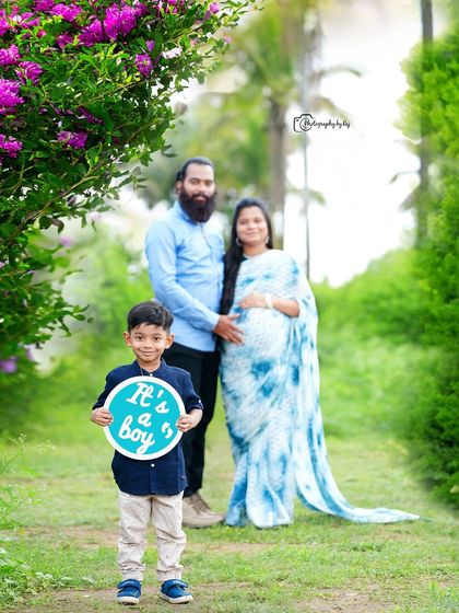 A happy family gender reveal photo. The older son holds a sign announcing "It's a boy!" in our beautiful garden.