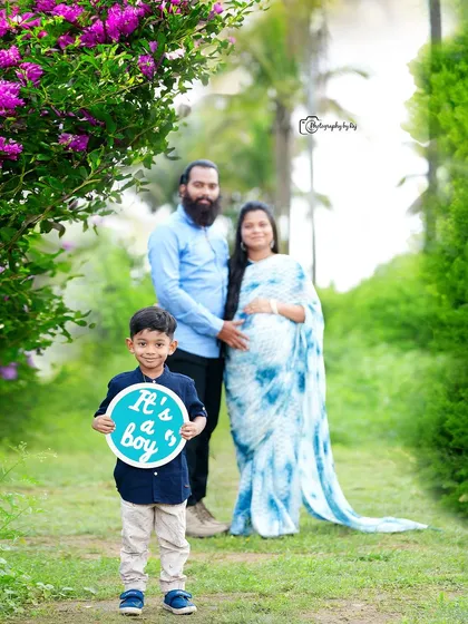 A happy family gender reveal photo. The older son holds a sign announcing "It's a boy!" in our beautiful garden.