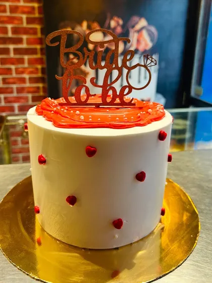 A simple and sweet "Bride to be" cake with a red glitter topper and tiny red hearts.