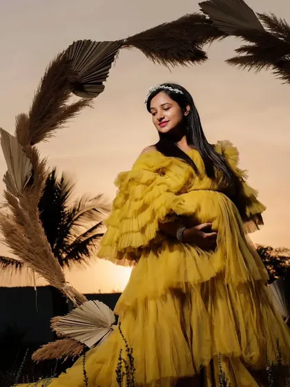Shine bright in this vibrant yellow ruffled gown, captured here during a golden hour sunset. The cheerful color and playful layers of tulle bring joy and energy to your maternity photos, creating images you'll treasure.
