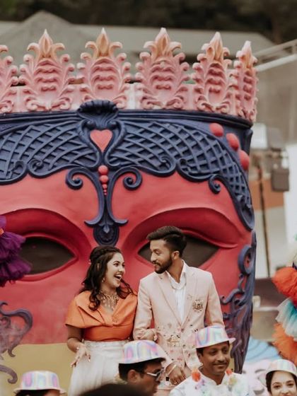 A wide shot capturing the couple on stage amidst the grand and colorful decor of their carnival party.