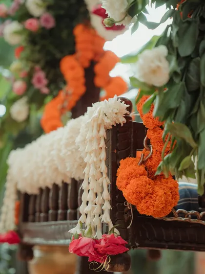 A detail shot of the cradle, showing how pops of colorful flowers and delicate jasmine garlands add charm and grace to the ceremony's focal point.