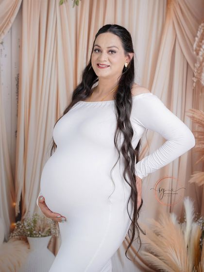 A radiant solo portrait in our boho-themed studio. The mom-to-be looks stunning in a simple white gown that beautifully accentuates her baby bump.