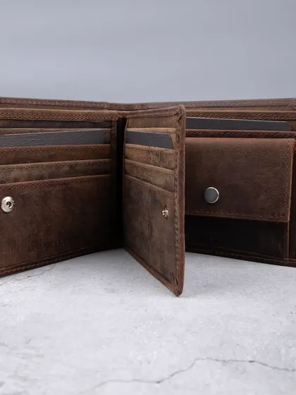 The interior of a distressed leather wallet, showcasing its coin pocket, card slots, and flip-up section for maximum functionality.