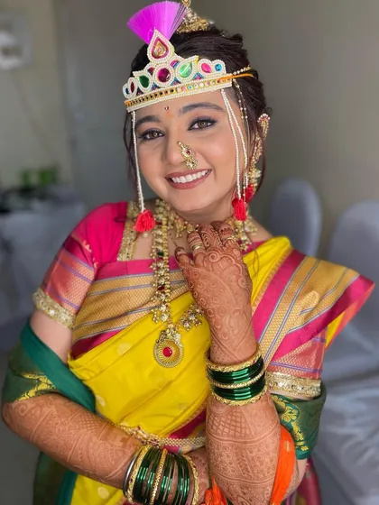 A full portrait of the bride in her yellow and pink saree, looking absolutely joyful and ready for her wedding.
