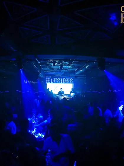 A wide shot of me on the decks at Club Illusions, with the entire venue bathed in deep blue light, creating a cool, immersive vibe.