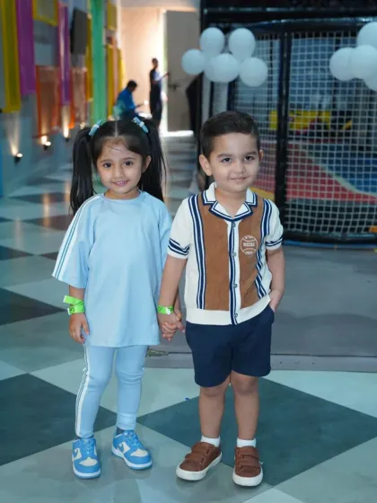Two adorable young guests hold hands at a race car-themed party. Our events are a great place for little ones to make new friends.