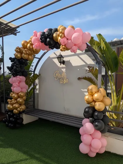 The completed balloon arch from another angle, set against the modern architecture of the terrace.