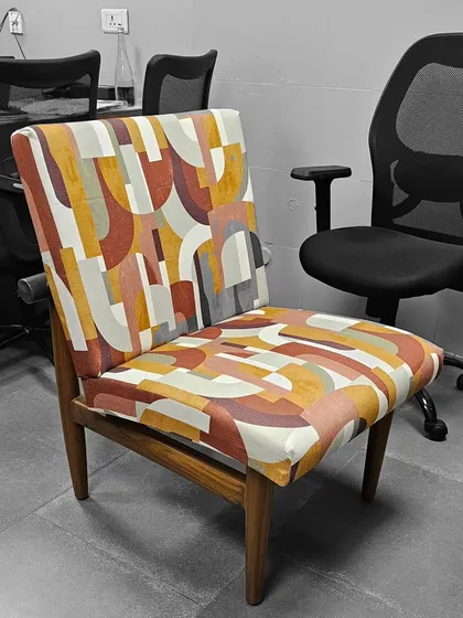 We also offer custom-made accent chairs. This piece features a bold, abstract fabric pattern on a simple wooden frame, adding a splash of color to the room.