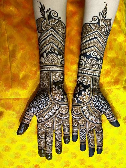 A gorgeous engagement mehendi featuring elegant peacocks at the top of the forearm. The design uses negative space to highlight the floral and geometric details, making it stand out beautifully.