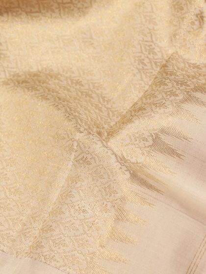 A regal cream Kanjivaram with a maroon border, featuring handwoven floral motifs in a mix of silver and gold zari.