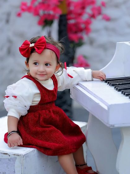 A little girl in a beautiful red dress playing our miniature white piano. This classic and elegant setup is perfect for timeless portraits.