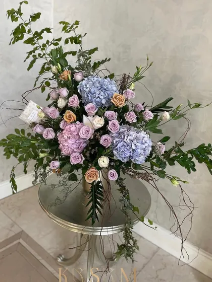 Marshmallow dreams in a vase. This large, airy arrangement features soft pastel hydrangeas and roses, accented with wild, woody stems. It’s designed to evoke the feeling of sweet, soft daydreams and simple wonders.