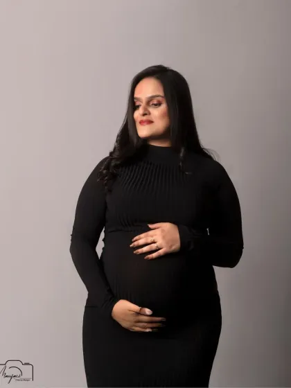 A gentle and loving portrait, as she cradles her bump. The simple grey background keeps the focus entirely on her.
