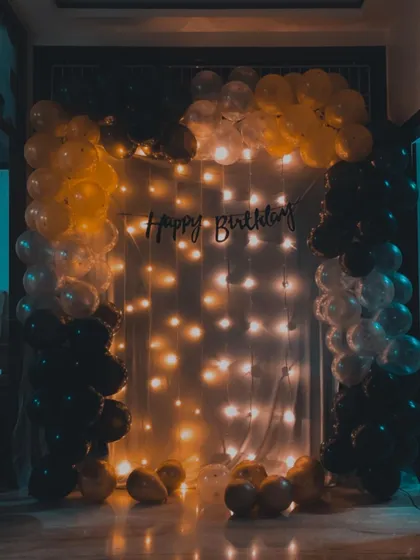 A moody, atmospheric shot of the black, gold, and silver birthday setup. The cool-toned lighting gives the classic party decoration a modern and stylish look.