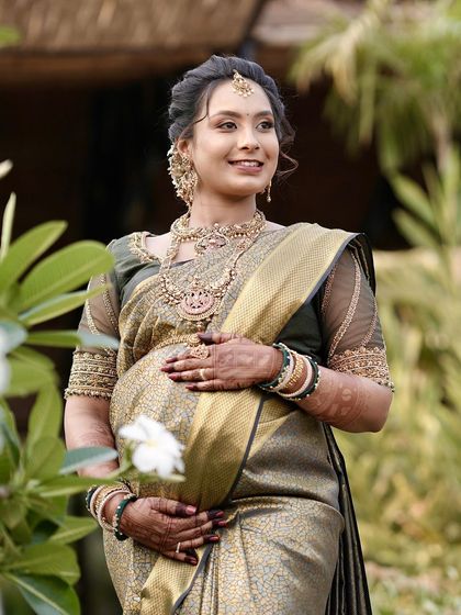 A lovely portrait of an expectant mother, her hands gently holding her baby bump. The mehendi on her hands and forearms adds a beautiful, traditional touch to this special moment.