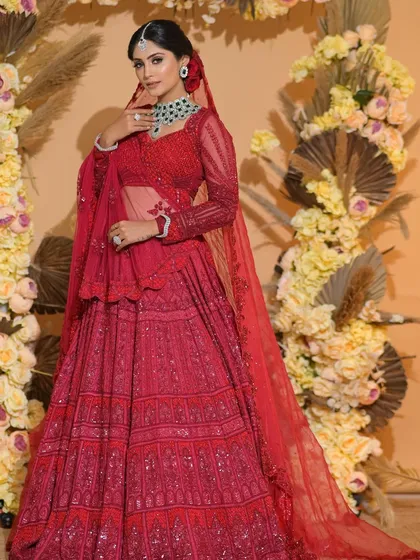 A full-length view of this classic red bridal look. The bride looks absolutely regal against the beautiful floral backdrop.