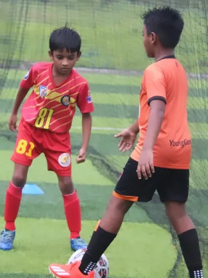A U9 player dribbling under pressure from an opponent.