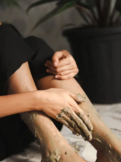 A shot focusing on the application of the mud to the legs and feet, showing the product's versatility.