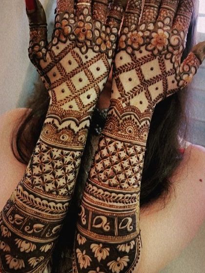 A rich, dense mehendi design featuring bands of lotus flowers and elephants. The palms are covered in intricate jaal work, creating a stunning look for any festive occasion.
