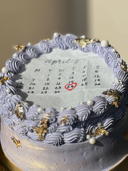 A lavender-colored burn away cake with gold leaf accents. The vintage piping and pearl details make it an elegant choice for a surprise celebration.