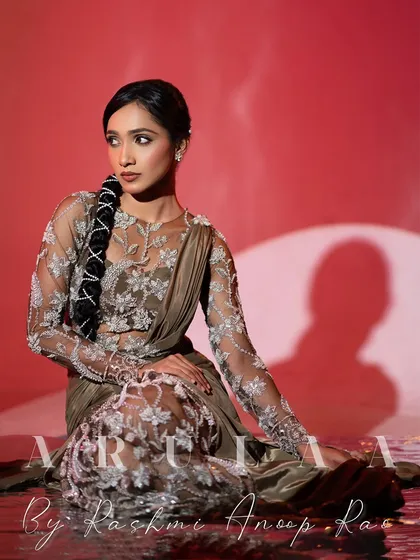 A stunning studio shot of the olive green draped saree gown. The intricate silver floral embroidery on the sheer fabric creates a beautiful illusion effect.