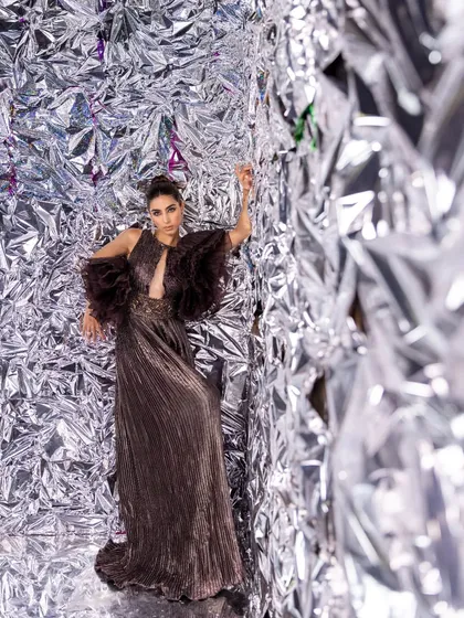 A dynamic shot from the Kalki Fashion editorial. The pleated metallic fabric and ruffled shoulder detail create a look that is both edgy and high-fashion.
