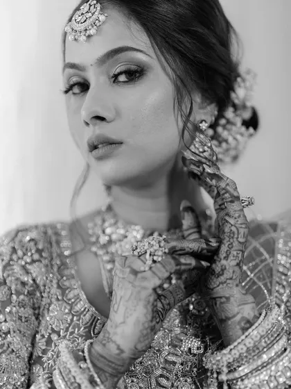 A classic black and white bridal portrait of Rashmi. The close-up focuses on her intricate henna, stunning jewelry, and her poised, confident expression.