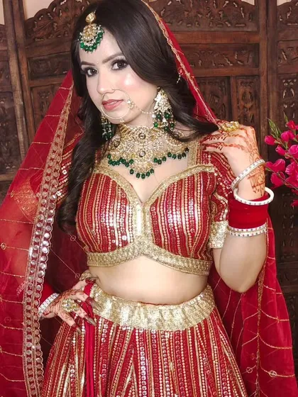This red and gold striped blouse and lehenga set offers a unique, modern take on bridal wear. It's paired with a heavy green beaded jewellery set.