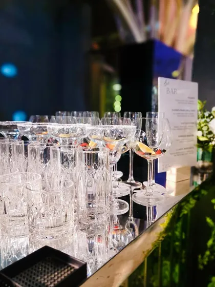 Another angle of our glassware, reflecting the lush greenery and ambient light of the event. We believe presentation is just as important as the drink itself.