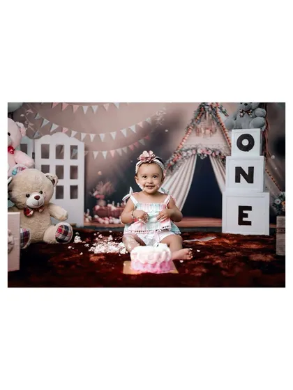 A sweet smile after the cake smash. This little girl is enjoying her first birthday cake in a cozy, festive tent setup, making for a perfect milestone photo.