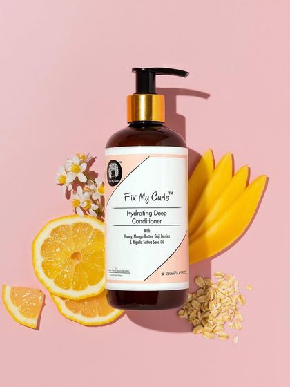 This vibrant flatlay uses a bright pink background to make the ingredients shine. The hydrating conditioner is surrounded by lemon, mango, and oats, creating a colorful and appealing composition.