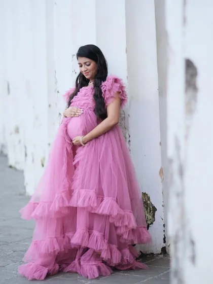 A quiet, contemplative moment. The soft layers of this pink ruffled tulle gown create a beautiful texture and shape, perfect for an elegant and timeless maternity portrait.