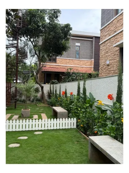 The balance of formal and informal planting at Chaithanya Samarpan. The manicured lawn and picket fence contrast beautifully with the more naturalistic planting of canna lilies and other flowering shrubs.