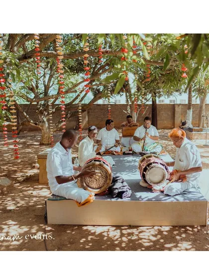 Traditional Nadaswaram musicians playing under the shade of a mango tree, adding an authentic and auspicious soundtrack to the backyard wedding.